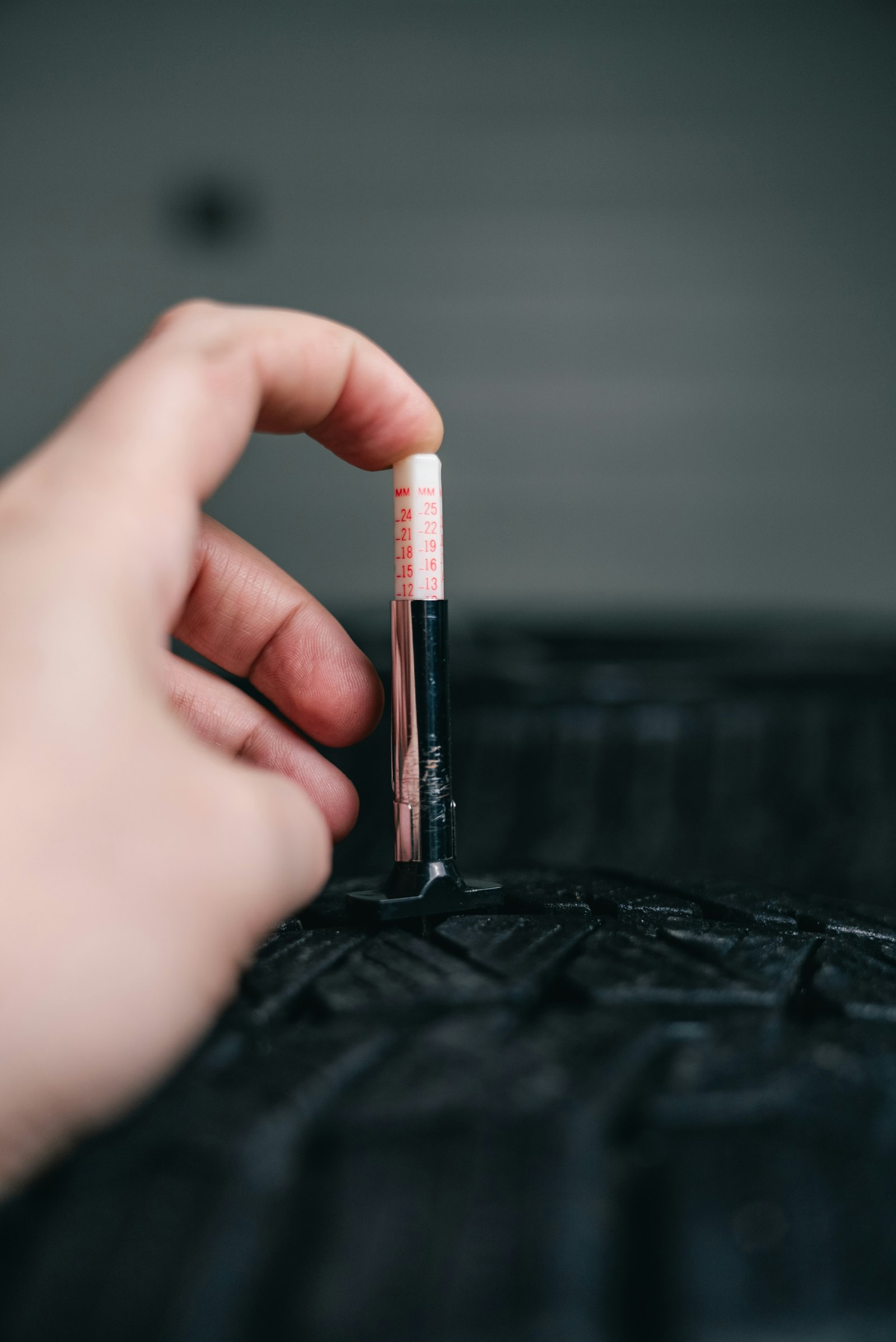 Mechanic checking tire tread depth with a gauge